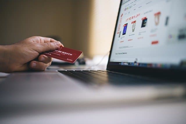 Hand holding a credit card next to an open laptop